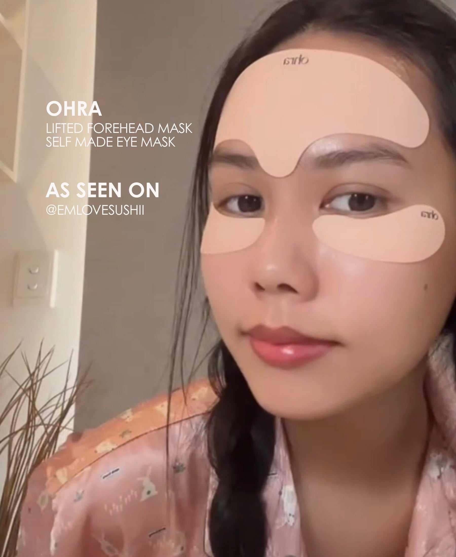 Ohra Lifted Forehead Mask as seen on, reusable, medical-grade silicone, Australia. Girl smiling in a selfie with reusable masks on. A woman wearing peach-colored eye mask patches under her eyes and on her forehead, wearing a pink patterned pajama top. Text overlays on the left read 'OHRA LIFTED FOREHEAD MASK SELF MADE EYE MASK' and 'AS SEEN ON @EMLOVESUSHII'.