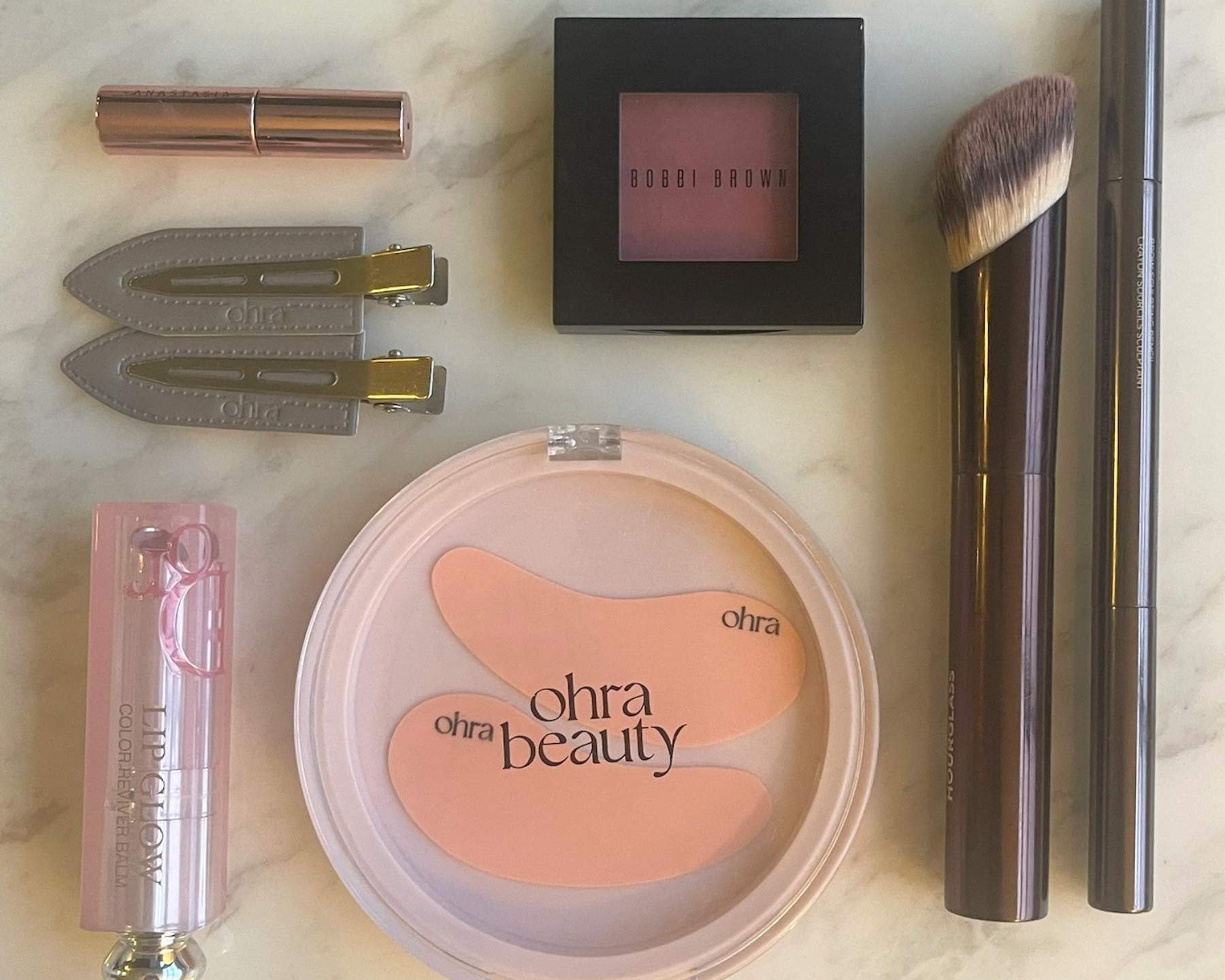 The Gift Set flat lay, Self Made Eye Mask and Untouched Hair Clips styled with makeup products on marble surface