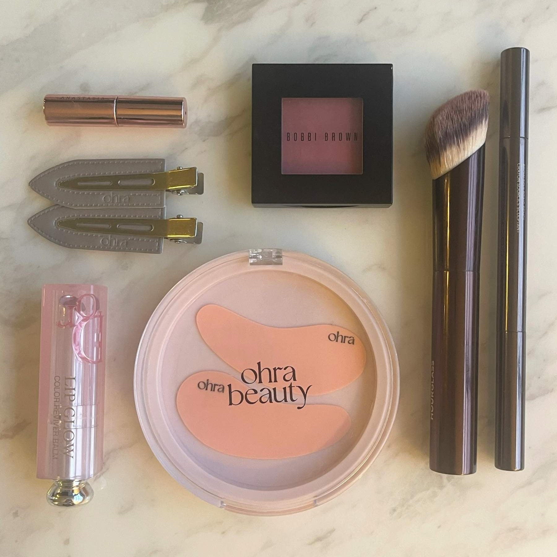 The Gift Set flat lay, Self Made Eye Mask and Untouched Hair Clips styled with makeup products on marble surface