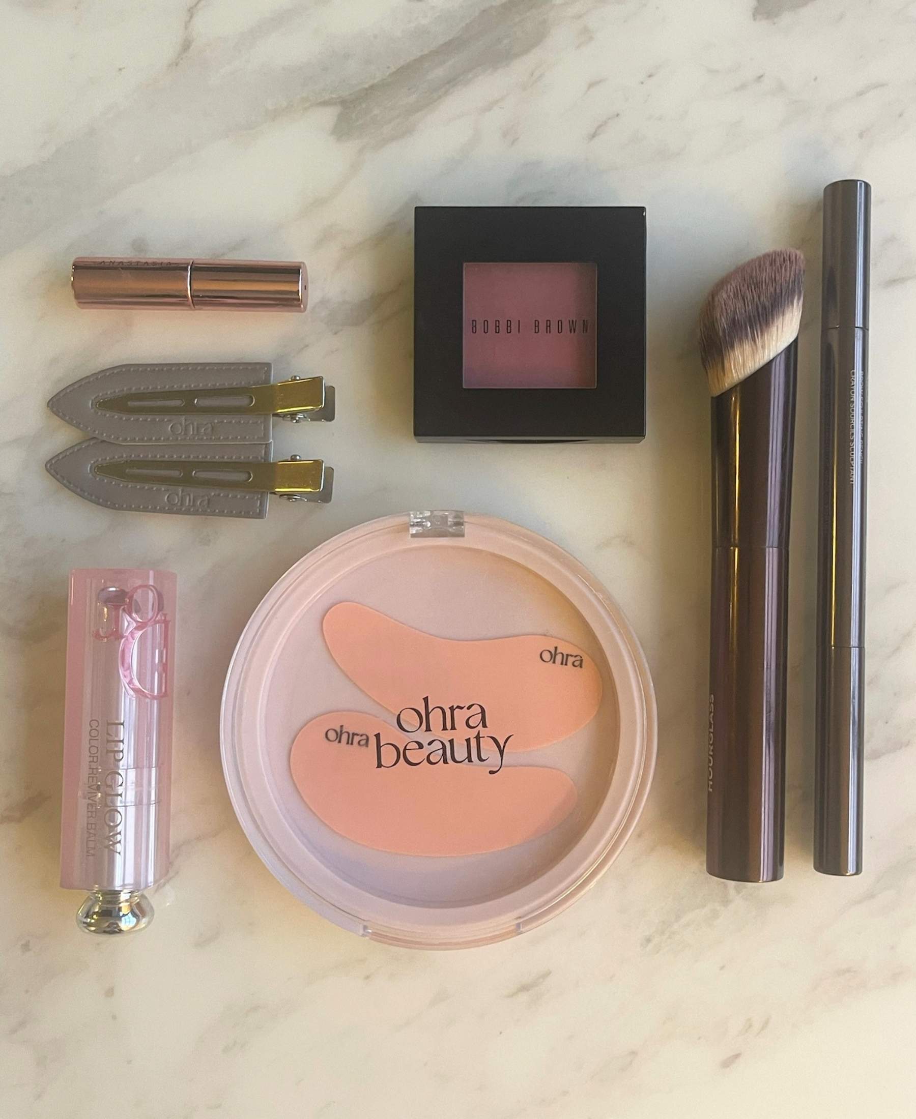 The Gift Set flat lay, Self Made Eye Mask and Untouched Hair Clips styled with makeup products on marble surface