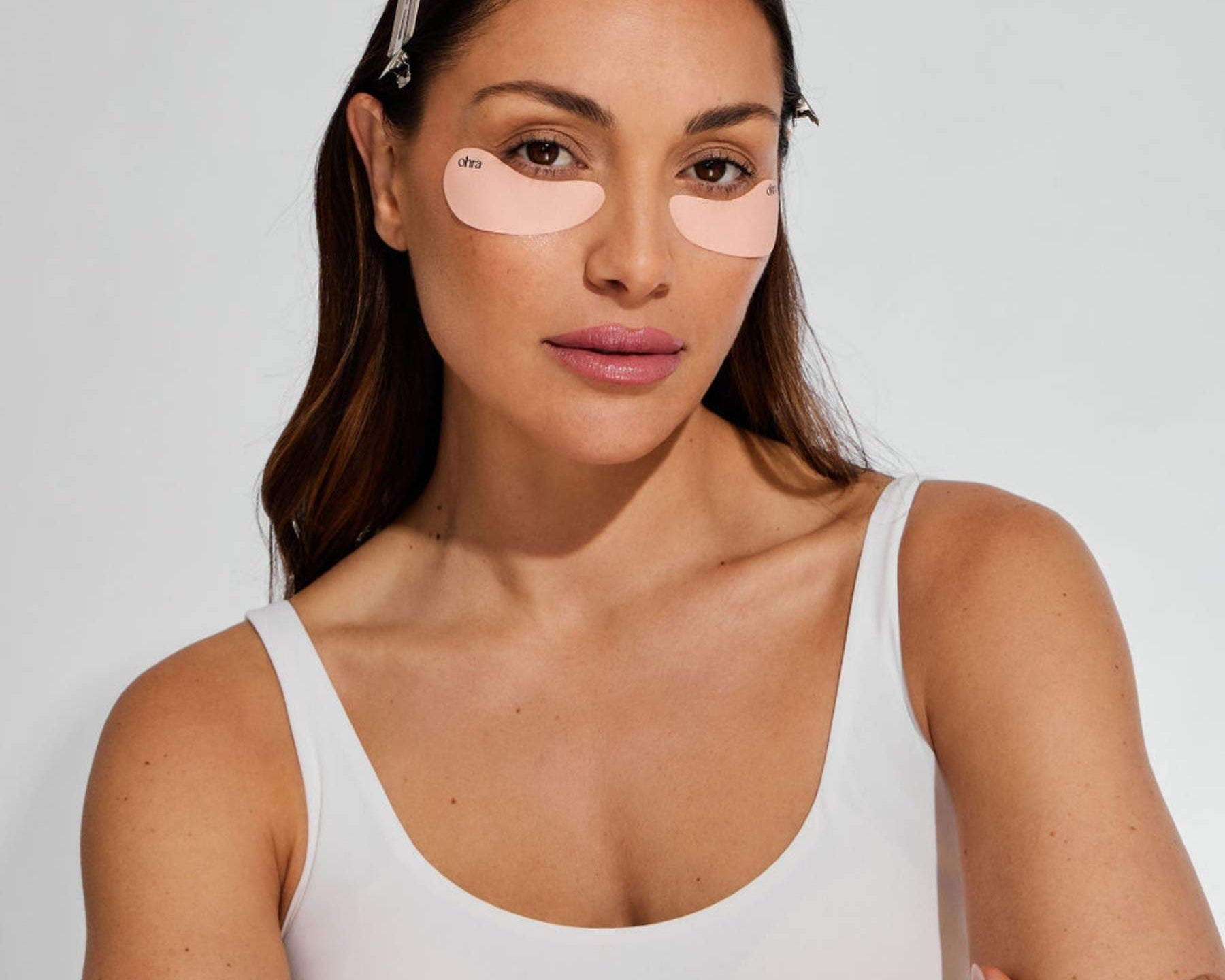 Woman wearing the reusable Ohra Self Made Eye Mask during her morning skincare routine, de-puffing and hydrating under-eyes