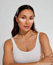 Woman wearing the reusable Ohra Self Made Eye Mask during her morning skincare routine, de-puffing and hydrating under-eyes